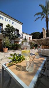 a table with a glass of lemonade and a vase on it at Hotel La Bastide in Le Lavandou