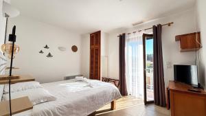 a white bedroom with a bed and a television at Hotel La Bastide in Le Lavandou