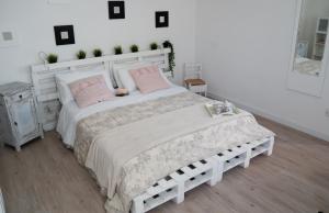 a white bedroom with a large bed with pink pillows at Mirella's House in Padova