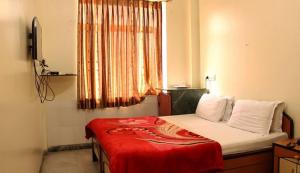 a bedroom with a bed with a red blanket on it at Hotel Neelkamal in Indore