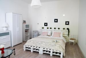 a white bedroom with a large bed with pink pillows at Mirella's House in Padova +18 photos