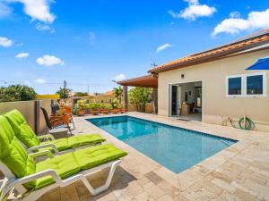 a swimming pool with chaise lounge chairs and a house at Villa Savannah in Savaneta