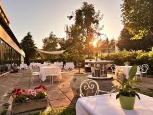 a patio with tables and chairs and the sun setting at Hotel Castello Artemide Congressi in Castel San Pietro Terme