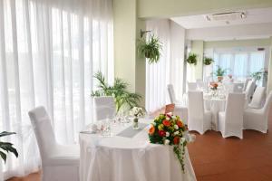 a banquet room with white tables and white chairs at Hotel Castello Artemide Congressi in Castel San Pietro Terme