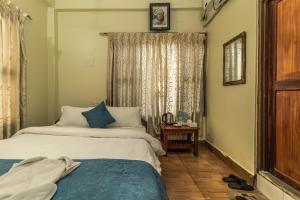 a bedroom with two beds and a table and a window at Hotel Aahar chitawan in Bharatpur
