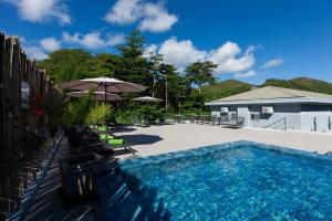 a swimming pool with chairs and umbrellas next to at Cote d'Or Retreat in Anse Volbert Village