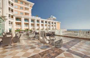 a patio with chairs and tables and a building at Litore Resort Hotel & Spa - Ultra All Inclusive in Okurcalar