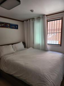 a bedroom with a white bed with a window at 러너리 스테이 in Seoul