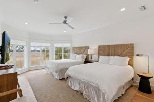 two beds in a bedroom with white walls and windows at Sunset Peak - 1928 Ocean Road in Saint Simons Island +52 photos