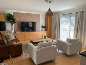 a living room with a couch and chairs and a tv at The Little Cove in Strand