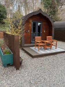 a small cabin with two benches in front of it at Go Glamping at Inverness & Loch Ness in Inverness