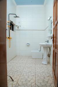 a white bathroom with a sink and a toilet at Kivu Breeze Apartment in Gisenyi