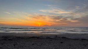 a sunset on a beach with the ocean at Shelley Cove in Stompneusbaai +6 photos
