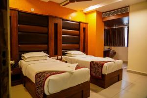 two beds in a room with orange walls at Tree Inn Jubilee in Hyderabad +5 photos