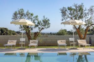 a group of chairs and umbrellas next to a pool at Masseria Bandino & Spa in Otranto