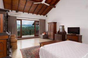 a bedroom with a bed and a television and a balcony at Villa Subashri, Victoria Golf Greens - Digana in Kandy