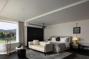 a bedroom with a bed and a couch and a window at Arcadia Small courtyard in Dali Shuanglang