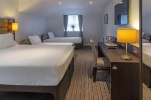 a hotel room with two beds and a desk at Best Western Leicester Oadby in Great Glen