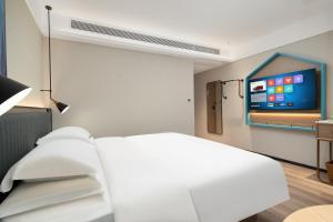 a bedroom with a white bed and a flat screen tv at Echarm Hotel Guangzhou East Railway Station South China Normal University Metro Station in Guangzhou