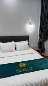 a bed with a blue and yellow sign on it at Boston Grand hotel in Osh