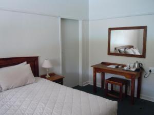 a bedroom with a bed and a desk with a mirror at Colesberg Lodge in Colesberg