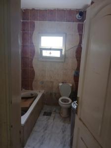 a bathroom with a tub and a toilet and a window at Share Apartment but Private Room in Madinat Al Ashir min Ramadan