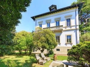 a large white building with benches in front of it at Emy charming apartment with pool in Verbania