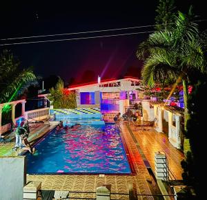 a swimming pool in front of a house at night at Vine Gardens & Hotel, Mityana in Mityana +5 photos