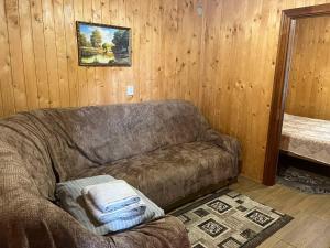 a living room with a brown couch in a wooden wall at Санаторий "Синяк" гостиный двор "ПРОЛИСОК" in Sinyak