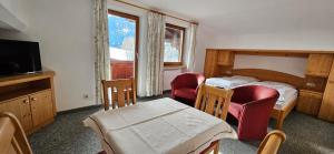a bedroom with two beds and two chairs and a television at Frühstückspension Schönblick in Ellmau