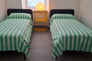 two beds in a room with green and white stripes at Appartamento Caffaro Vacanza in Ponte Caffaro
