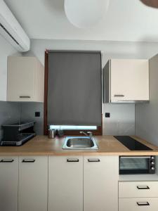 a kitchen with white cabinets and a sink at Hill Sun Luxury Suites in Nea Irakleia