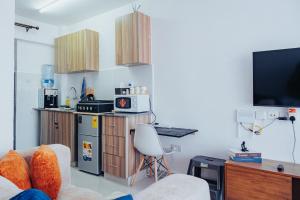 a living room with a couch and a kitchen with a tv at Work Friendly Studio near Nairobi CBD and Westlands in Nairobi