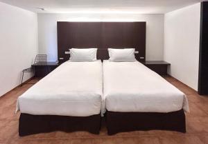 a bedroom with two beds with white sheets at Auberge de Oishi in Takamatsu