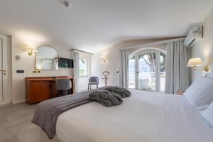 a bedroom with a large white bed and a desk at Hotel Excelsior Bay in Malcesine