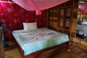 a small bed in a room with red curtains at Authentic Cambodian Angkor Cottage in Siem Reap