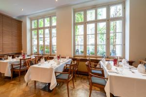 a restaurant with white tables and chairs and large windows at martas Hotel Allegra Berlin in Berlin