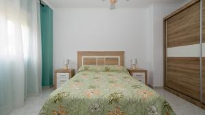 a bedroom with a bed with a green bedspread at Langosteira Beach, spacious apartment in Fisterra