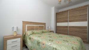 a bedroom with a bed with a green comforter at Langosteira Beach, spacious apartment in Fisterra +18 photos