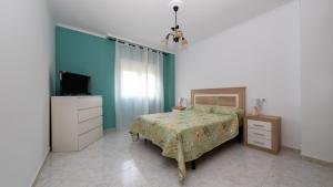 a bedroom with a bed and a dresser and a television at Langosteira Beach, spacious apartment in Fisterra