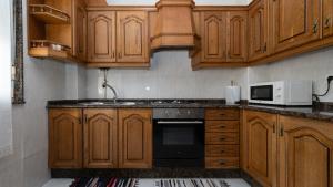 a kitchen with wooden cabinets and a microwave at Langosteira Beach, spacious apartment in Fisterra