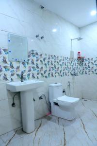 a white bathroom with a sink and a toilet at The Golden Farm in Jāmb