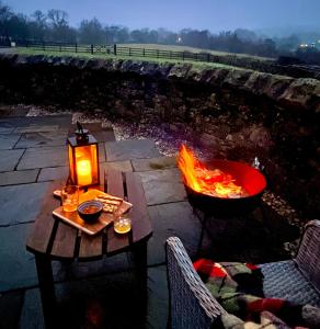 a fire pit with a wooden table and a lantern at Cosy Cottage for Two in the Peak District with Parking in Onecote
