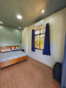 a bedroom with a bed and a window with blue curtains at Island Nest in Virac