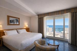 a hotel room with a bed and a view of the ocean at LVG Hotel Collection - Grand Hotel Mediterranee in Alassio
