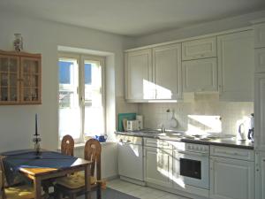 a kitchen with white cabinets and a table in it at Ferienwohnung Schwark Haus Elisabeth in Aschau im Chiemgau