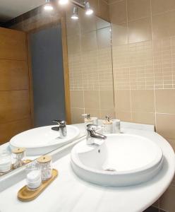 a bathroom with two sinks and a mirror at Living Sevilla & Parking gratis in Seville +5 photos