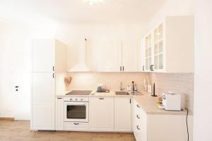 a white kitchen with white cabinets and a sink at Hofgassenhaus LIMUN in Mörbisch am See