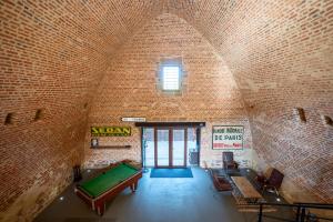 an empty room with a pool table in a brick wall at Le Magasin à Poudre in Rocroi