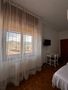 a bedroom with a window with white curtains at Portal De La Rioja in Haro
